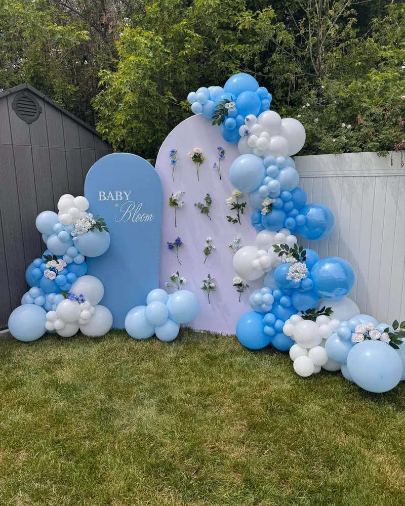 Baby in Bloom baby shower with blue and white balloons and fresh flowers on arched panels