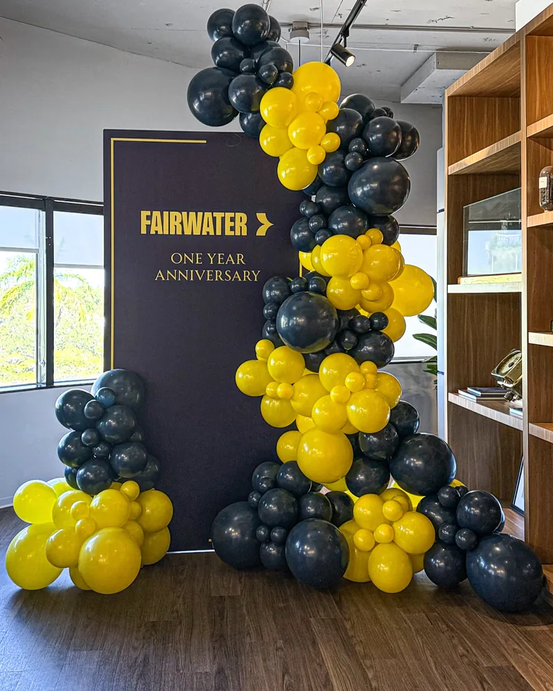 Company anniversary balloon garland in brand colours beside a printed backdrop