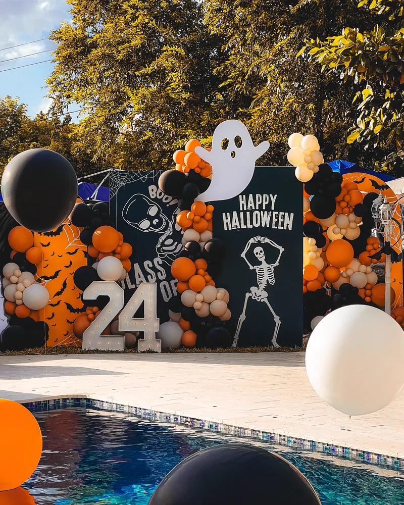 Halloween graduation party with poolside backdrops and light-up marquee numbers