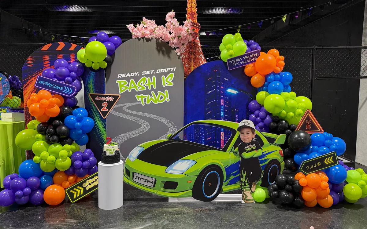 Racing themed second birthday with neon garland, printed panels and a car cutout