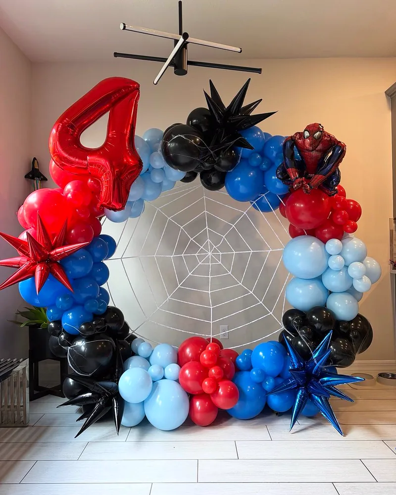 Superhero themed fourth birthday with a spider web backdrop and a red, blue and black balloon ring