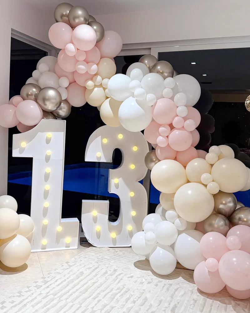 Light-up marquee number 13 beside a nude and chrome balloon garland