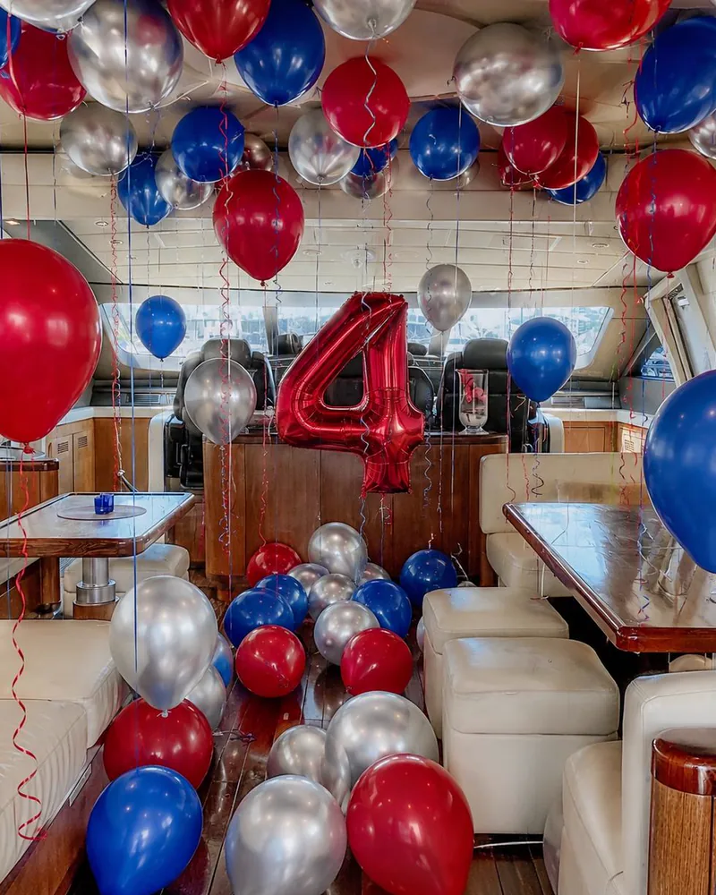 Yacht saloon filled with red, blue and silver helium balloons and a foil number four