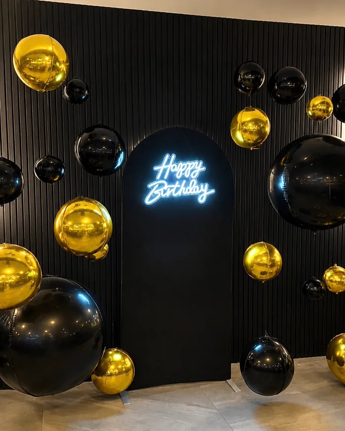 A Happy Birthday neon sign on an arched backdrop, available for rental