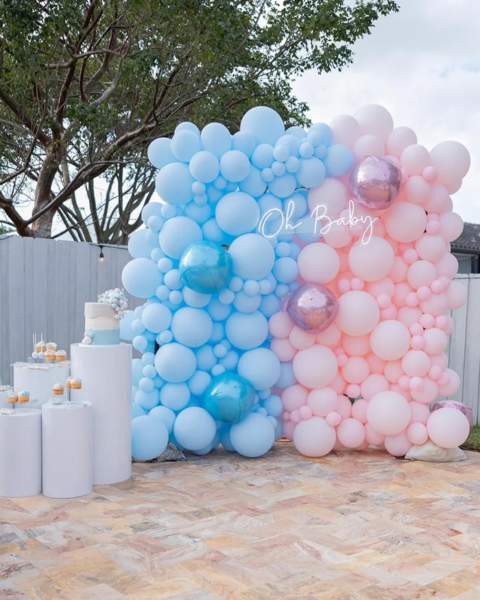 Plinths and cake stands staged in front of a balloon wall, available for rental